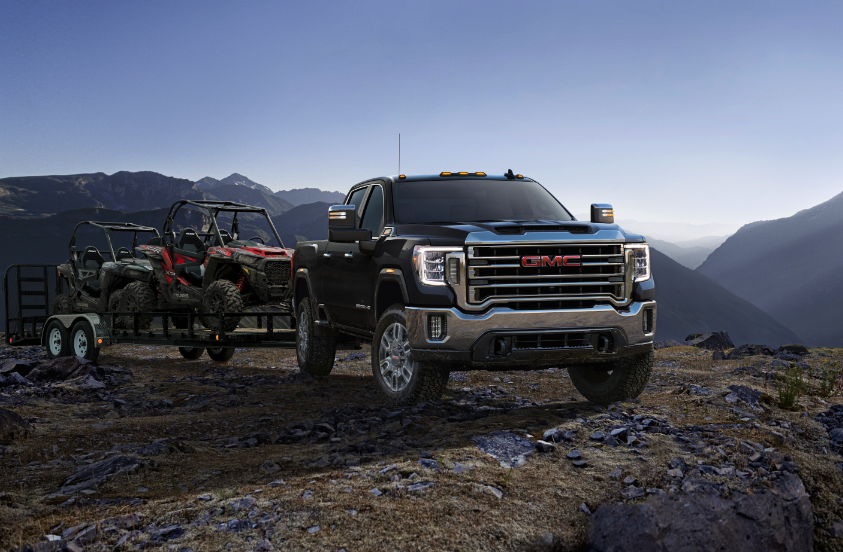 Gray 2023 GMC Sierra 2500 HD parked on rocky hill pulling trailer holding all-terrain cart
